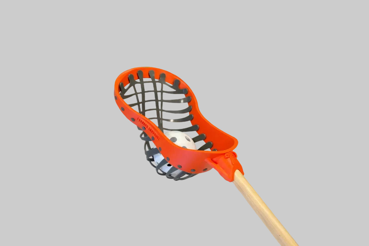 Orange lacrosse head with black strings on a white background